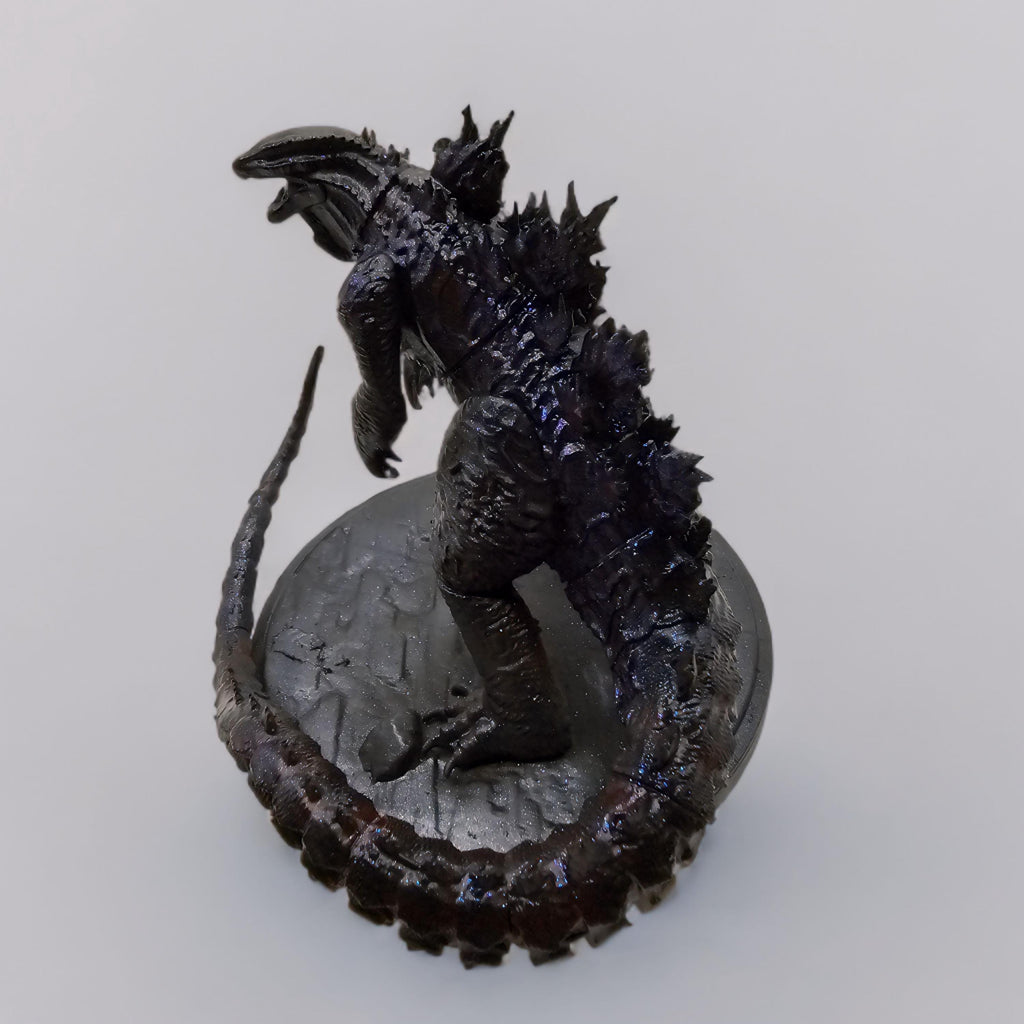 Hand-painted Shin Godzilla statue featuring dark, glossy detailing with jagged spines and a curled tail, standing on a textured circular base.