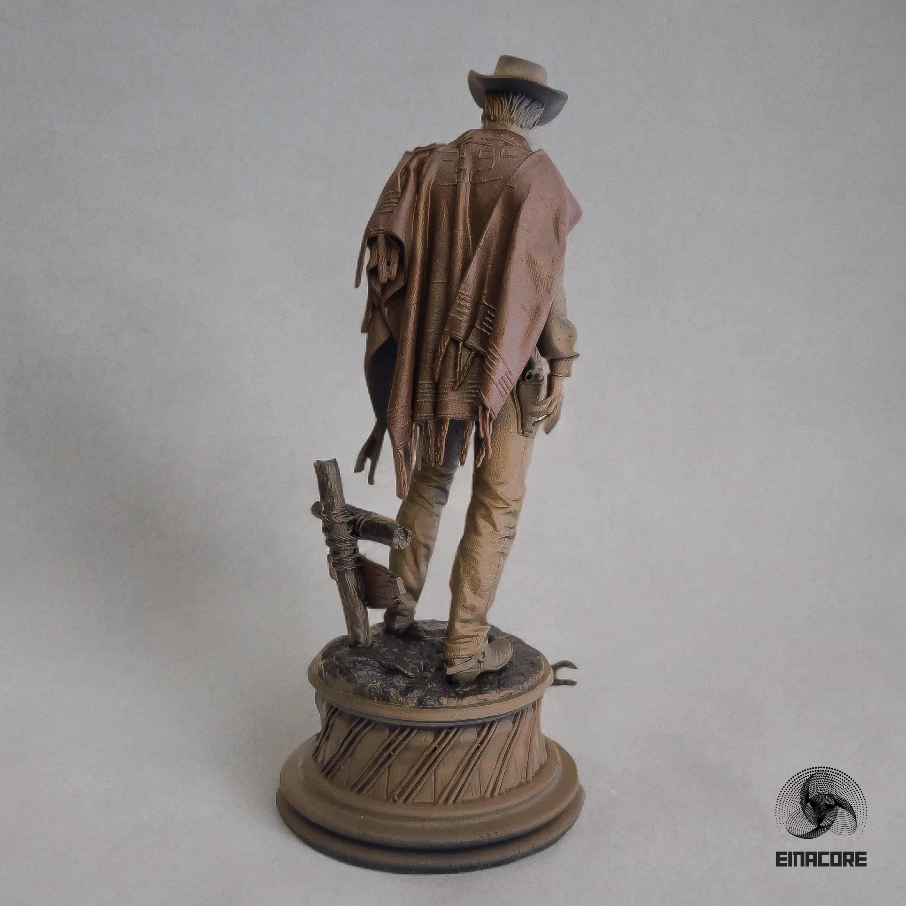 Statue of Clint Eastwood in a cowboy outfit, featuring a poncho, hat, and revolver, standing on a detailed round base with decorative elements.