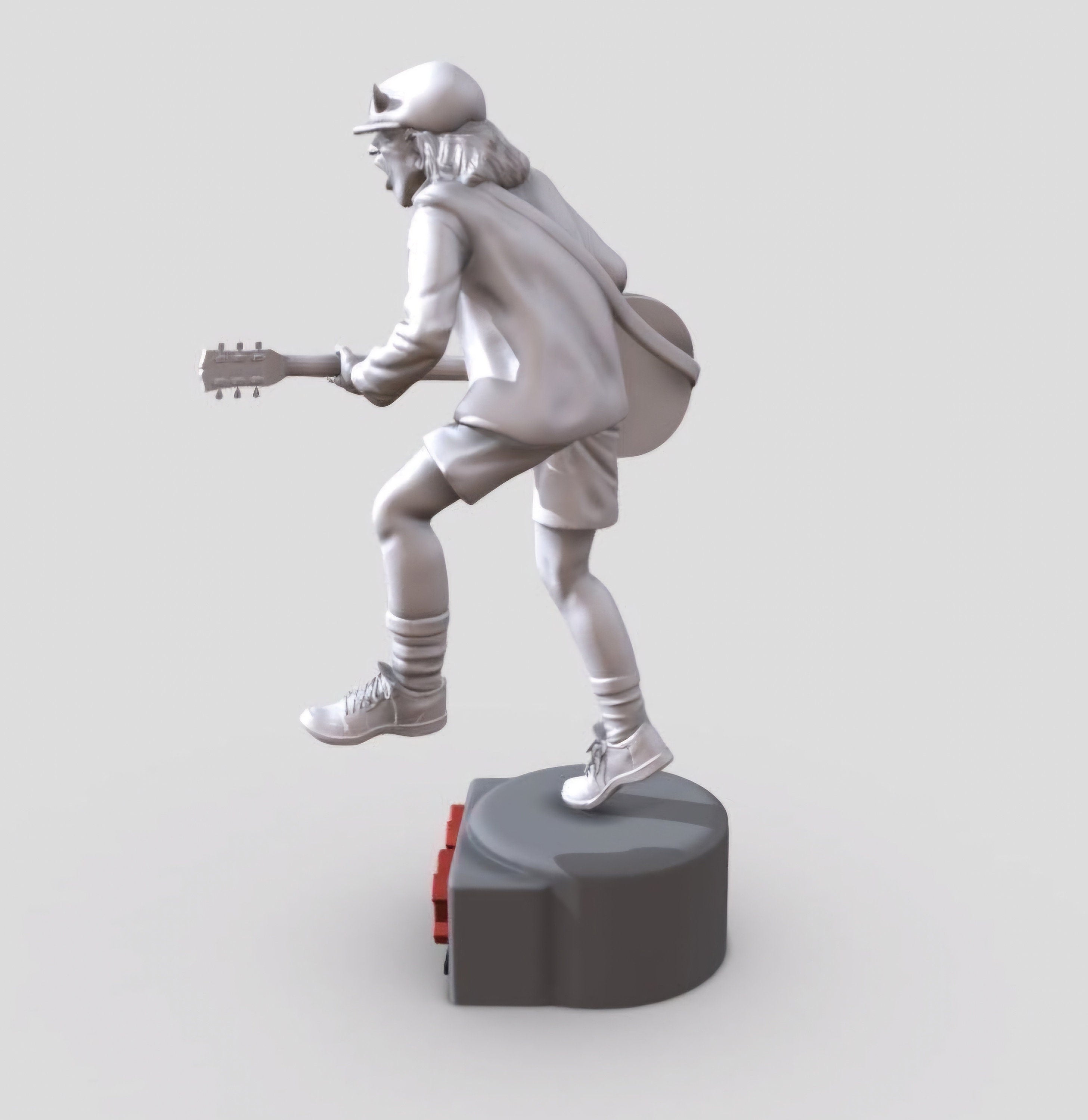 Statue of Angus Young from AC DC, depicted in a dynamic pose with his iconic guitar and schoolboy uniform, standing on a base engraved with the band&#39;s logo.