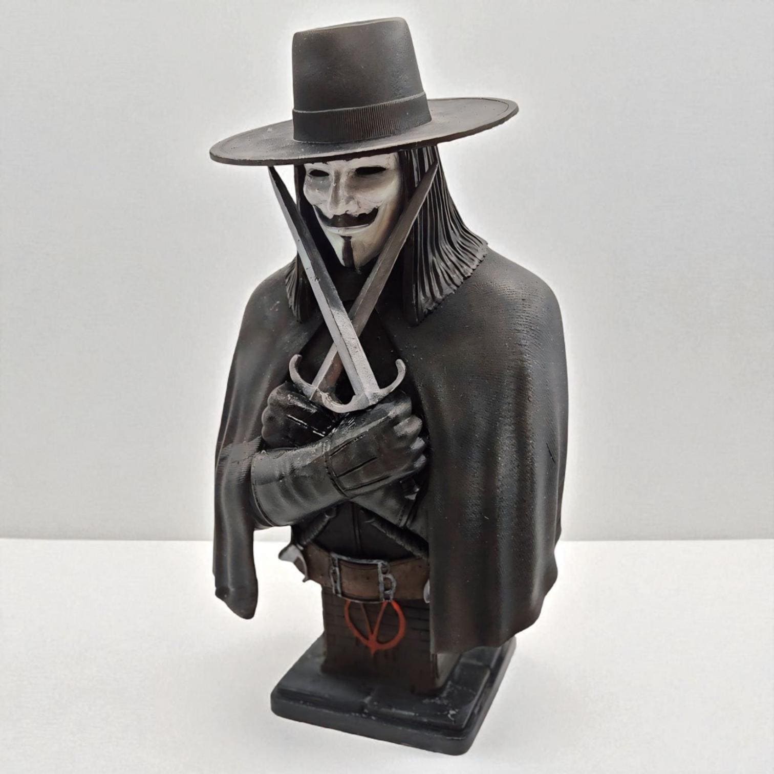3D-printed bust of Vendetta, featuring a masked figure in a wide-brimmed hat and cloak. The character holds two crossed daggers at the chest, embodying a mysterious and rebellious presence.