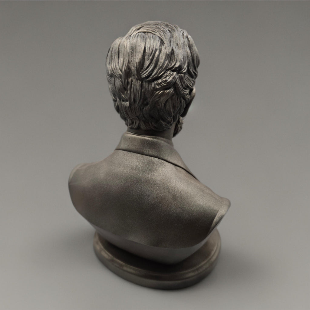 Silver-colored bust statuette of Abraham Lincoln, showcasing detailed facial features, a neatly trimmed beard, and formal attire with a bow tie, mounted on a rectangular base.