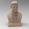 Detailed bust of John F. Kennedy, depicting the 35th U.S. president in a suit and tie with a serious, contemplative expression. The sculpture captures his distinctive hairstyle and strong features, mounted on a classic pedestal base.