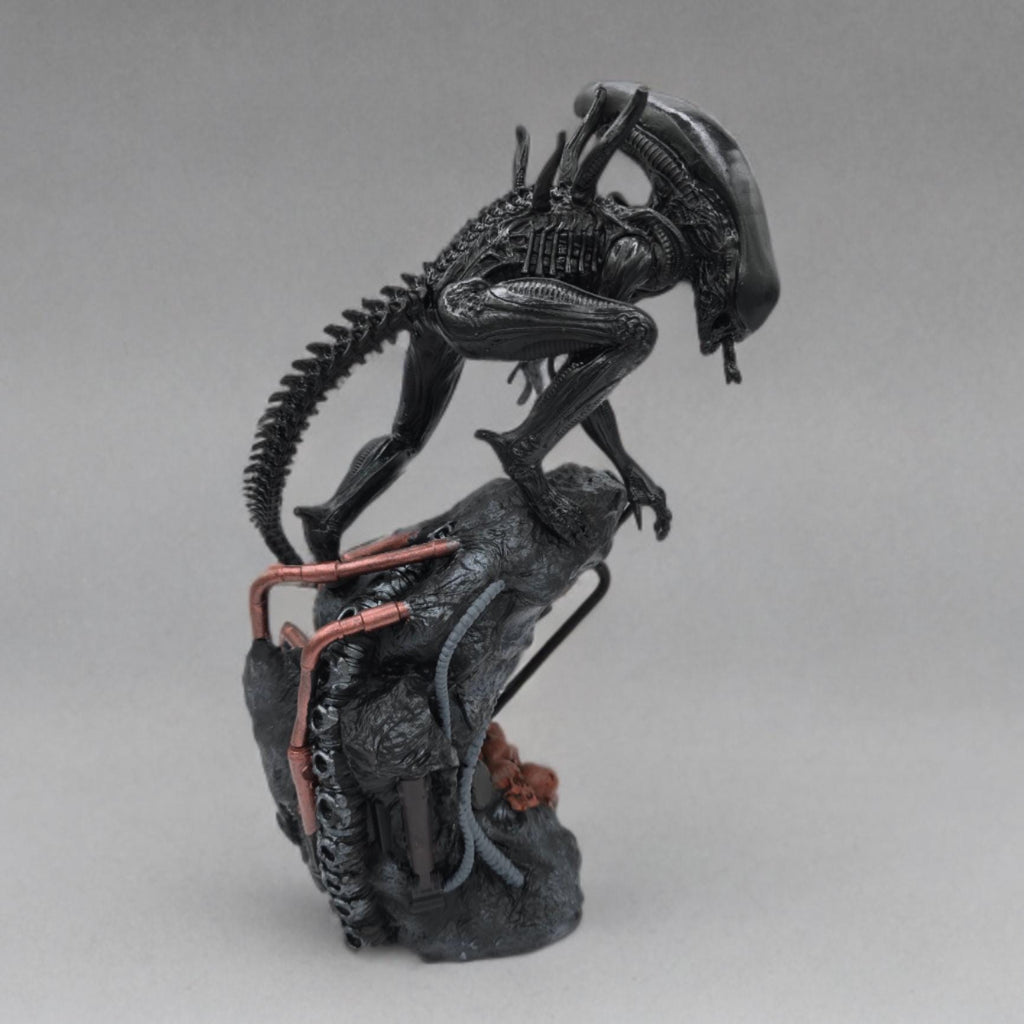Alien Exomorph Statuette featuring intricate biomechanical details, posed on a rocky base with skulls and metallic pipes, showcasing the creature’s iconic tail and menacing posture.