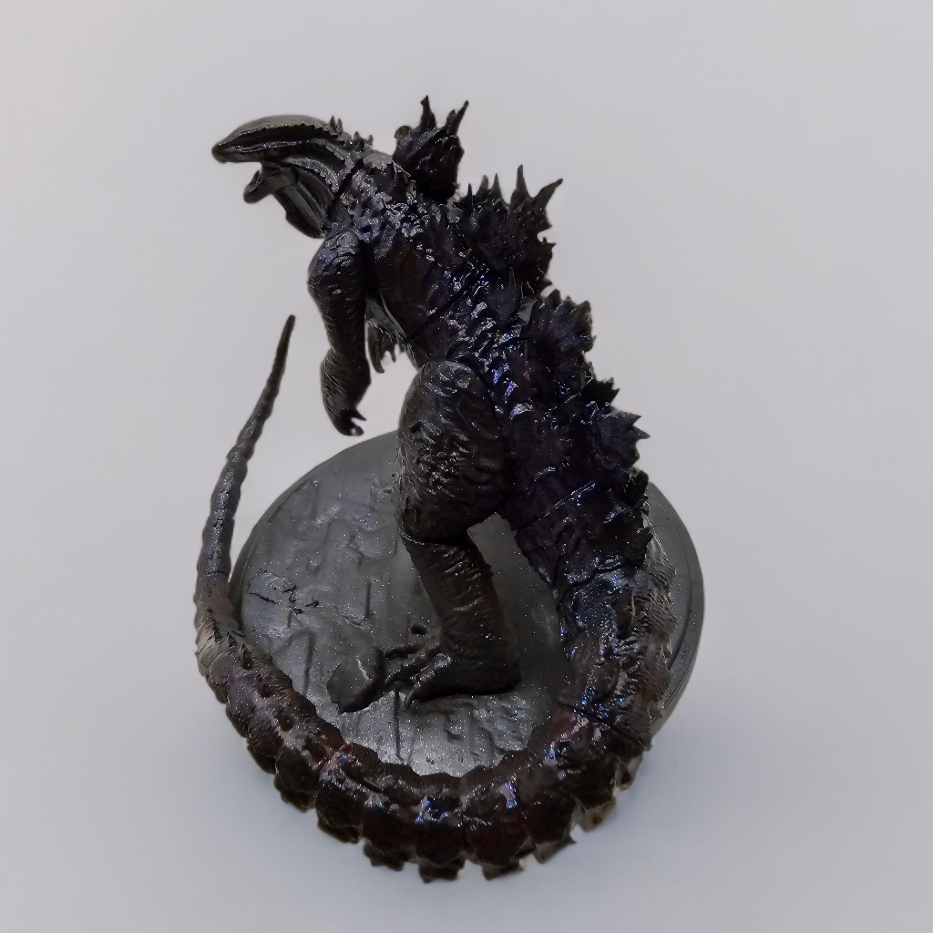 Hand-painted Shin Godzilla statue featuring dark, glossy detailing with jagged spines and a curled tail, standing on a textured circular base.