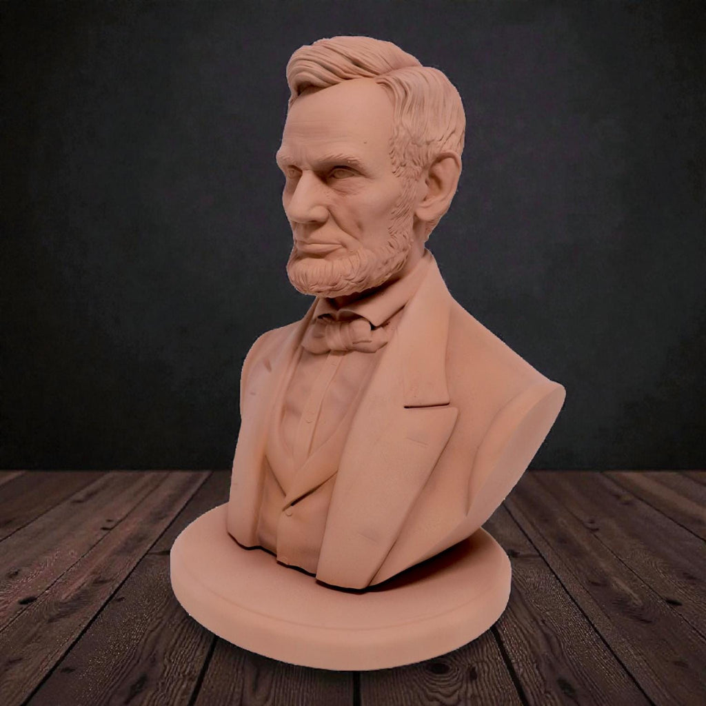 Silver-colored bust statuette of Abraham Lincoln, showcasing detailed facial features, a neatly trimmed beard, and formal attire with a bow tie, mounted on a rectangular base.