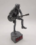 Statue of Angus Young from AC DC, depicted in a dynamic pose with his iconic guitar and schoolboy uniform, standing on a base engraved with the band's logo.