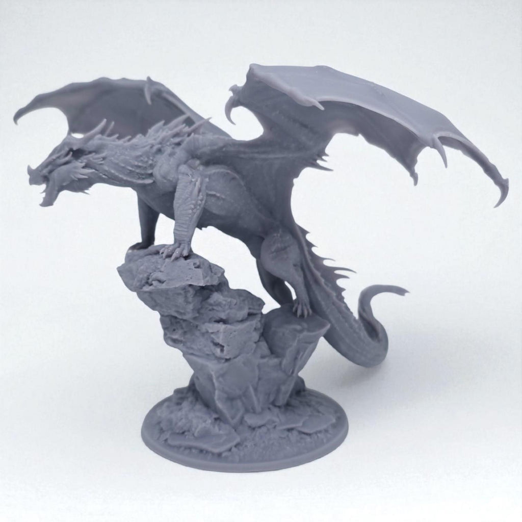 A fearsome Chromatic Red Dragon perches atop a rocky outcrop, wings spread wide and mouth open in a menacing roar. Its scales are rugged and spiked, exuding raw power and dominance. A perfect miniature for collectors and tabletop RPG enthusiasts.