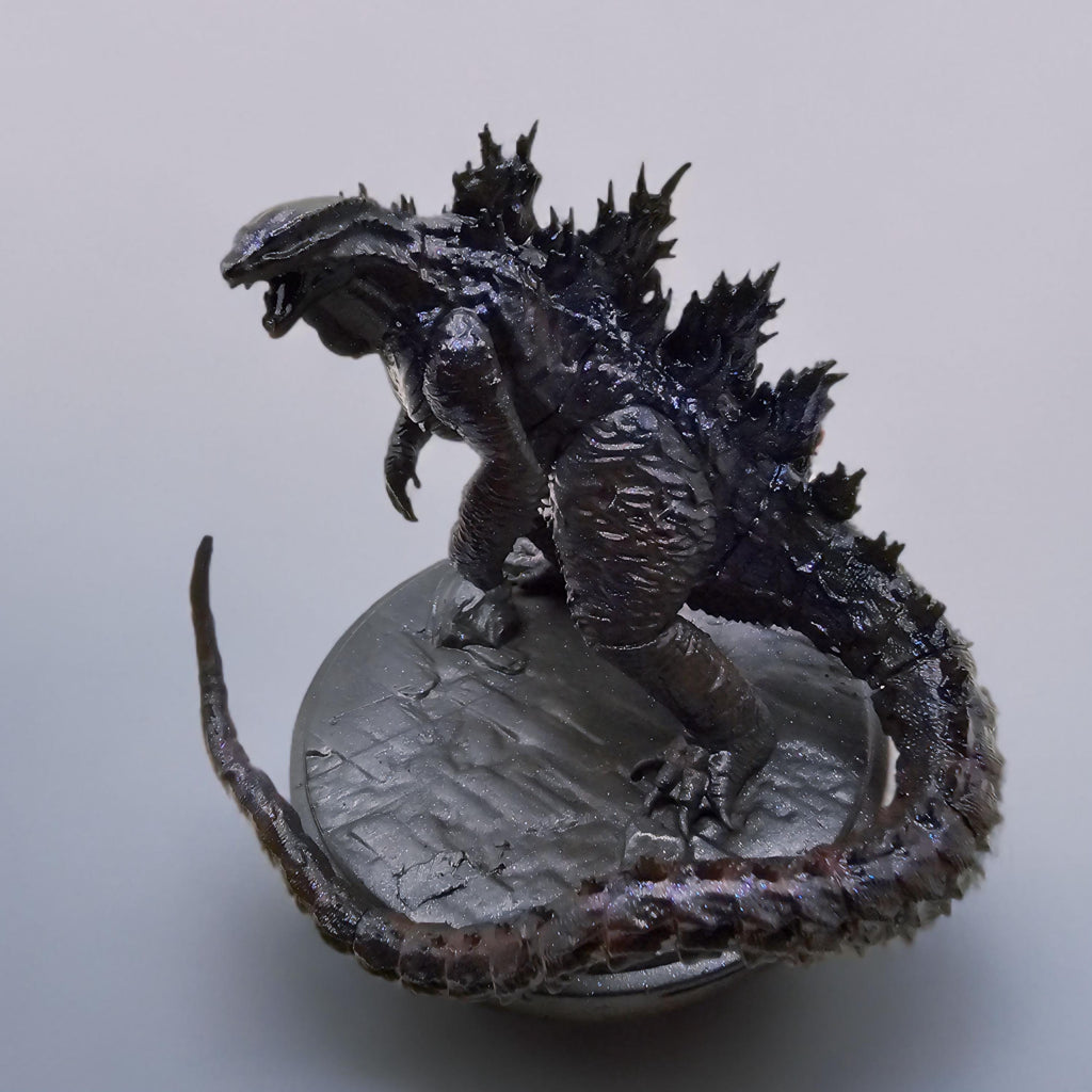 Hand-painted Shin Godzilla statue featuring dark, glossy detailing with jagged spines and a curled tail, standing on a textured circular base.