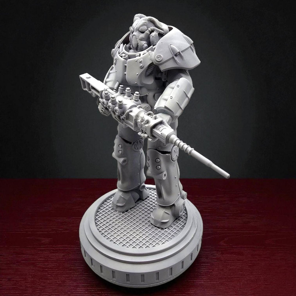 A gray plastic figurine of a robot wearing a helmet and holding a gun. The robot is standing on a round base with a textured surface.