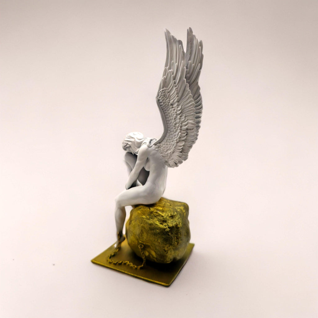 Statue of a chained angel seated on a textured pedestal, with detailed wings and a contemplative pose.